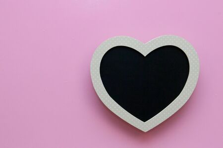 Blank heart shaped black board on a pink backgroundの写真素材