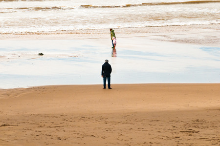 A child and grandparents play at the beach on a cold dayの写真素材