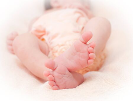 Close up of babies feet lying on a white sheetの写真素材