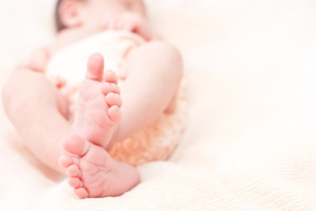 Close up of babies feet lying on a white sheetの写真素材