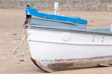 An old fishing boat moored on the beach at low tideの写真素材