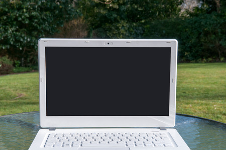 Modern laptop with a blank screen outside on a sunny day