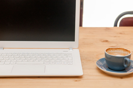 Fresh cup of coffee and laptop computer on a wooden table background in the cafeの写真素材