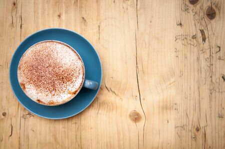 Cappucinno on a wooden cafe table viewed from aboveの写真素材