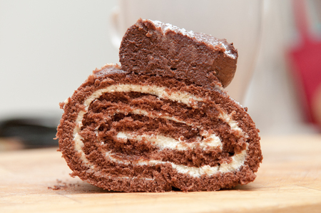 Slice of chocolate cake viewed from the side, in profile with a mug of coffee on a wooden boardの写真素材