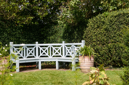 Garden furniture. Bench in a seating area of a formal gardenの写真素材