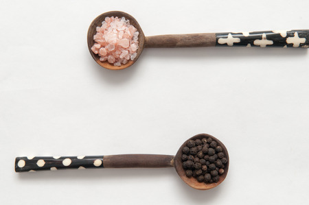 Salt and pepper seasonings of pepper corns and rock salt on wooden spoonsの写真素材