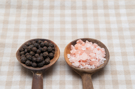 Salt and pepper seasonings of pepper corns and rock salt on wooden spoonsの写真素材