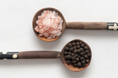 Salt and pepper seasonings of pepper corns and rock salt on wooden spoonsの写真素材