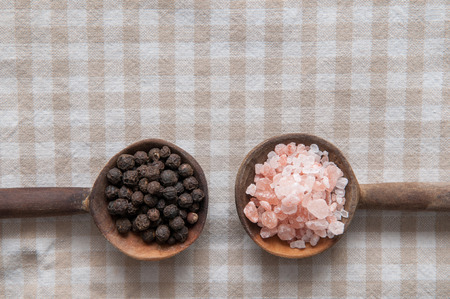 Salt and pepper seasonings of pepper corns and rock salt on wooden spoonsの写真素材