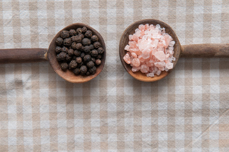 Salt and pepper seasonings of pepper corns and rock salt on wooden spoonsの写真素材
