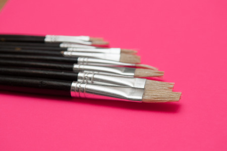 Artists brushes and pens displayed on isolated pink backgroundの写真素材