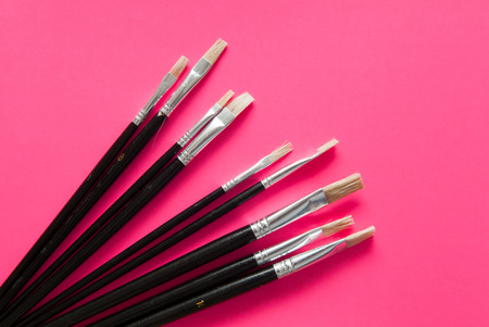 Artists brushes and pens displayed on isolated pink backgroundの写真素材