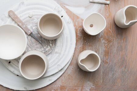 Overhead view of pottery in a ceramics workshop on a messy work table