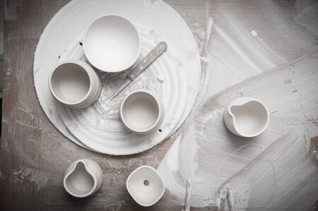 Overhead view of pottery in a ceramics workshop on a messy work tableの写真素材