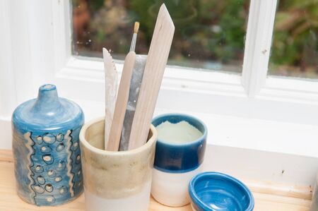 Pottery tools and vases on a window ledge in daylightの写真素材