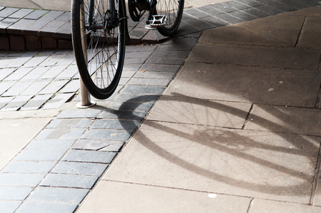 Bike locked up and casting a shadow on the pavementの写真素材