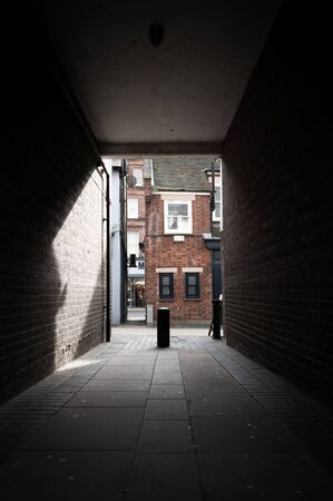 Looking down an alley with shadow cast on the wallの写真素材