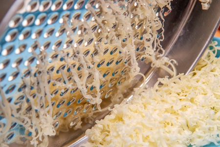 cheese being grated by a cheese grater close upの写真素材