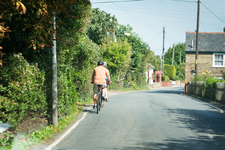 Cyclists ride bike through a quiet country laneの写真素材