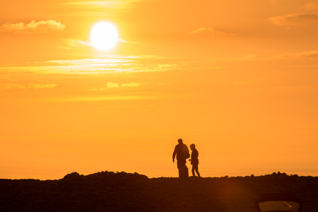 father and son watching the sunset together at the beachの写真素材