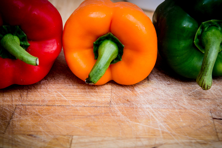 red green and yellow peppers on the chopping boardの写真素材