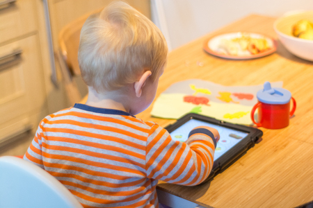 Child using a touch screen tablet to play learning gameの写真素材
