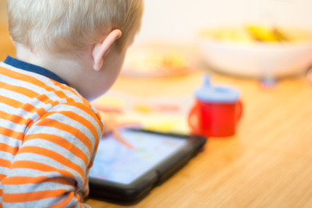 Child using a touch screen tablet to play learning gameの写真素材