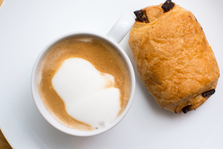 breakfast food on a plate, cappuccino coffee and chocolate croissantの写真素材