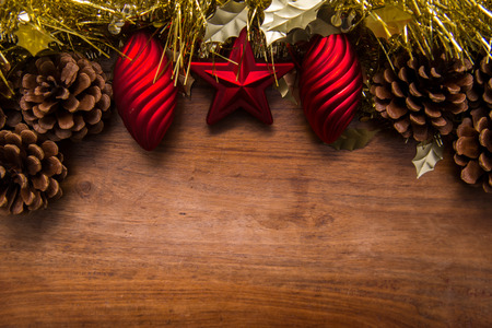 Christmas decoration border with gold tinsel and red baubles on wood backgroundの写真素材