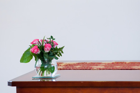 Empty room interior with white walls and wooden desk with flowersの写真素材