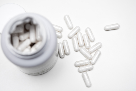 White tablets with an open bottle, some tablets are on the tableの写真素材