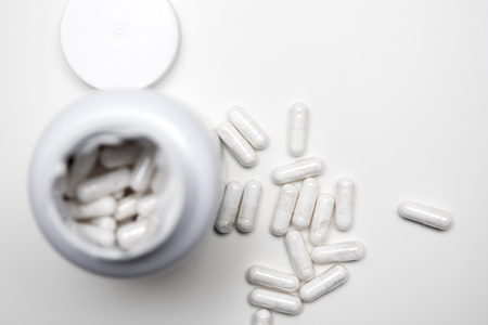 White tablets with an open bottle, some tablets are on the tableの写真素材