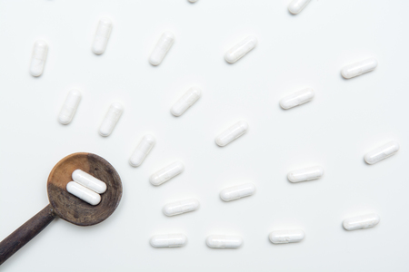 White tablets on a medicine dose spoon, with tablets across the tableの写真素材