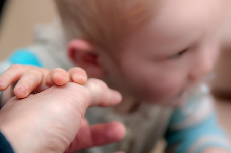 Baby learning to crawl. Holding hands with fatherの写真素材