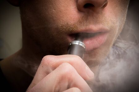 Man using a vape cigarette to smoke nicotineの写真素材