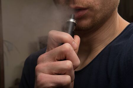 Man using a vape cigarette to smoke nicotineの写真素材