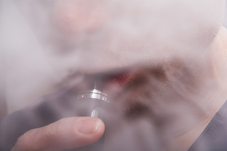 Man using a vape cigarette to smoke nicotineの写真素材