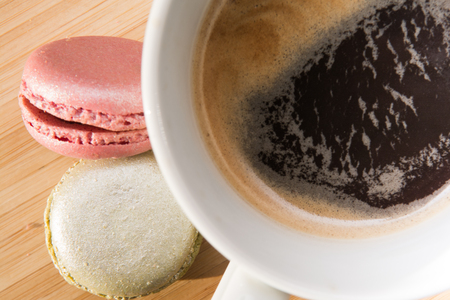 Coffee and macaroons on wooden table in sunlightの写真素材