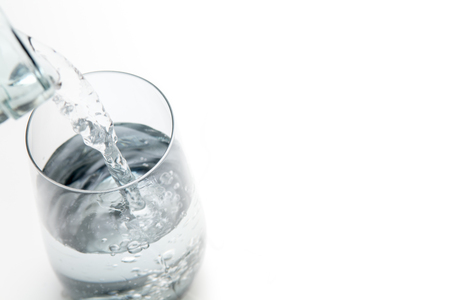 Drink more water. Water being poured from a bottle to glassの写真素材