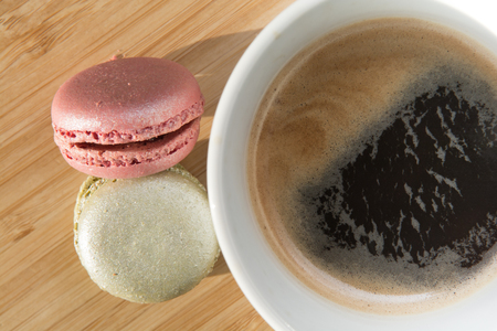 Coffee and macaroons on wooden table in sunlightの写真素材