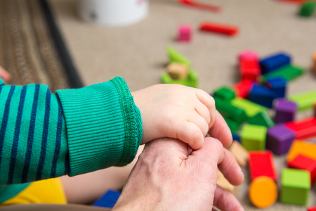 Child holding hands with father at homeの写真素材