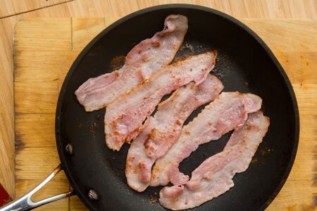 Streaky bacon cooking in the frying panの写真素材