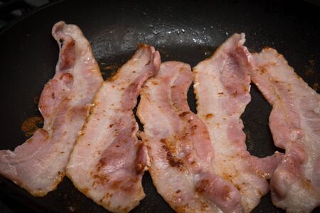 Streaky bacon cooking in the frying panの写真素材