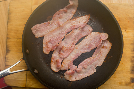 Streaky bacon cooking in the frying panの写真素材