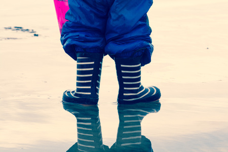 Child in a puddle of water wearing welly bootsの写真素材