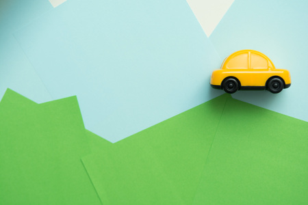 Yellow car driving over hills with blue sky backgroundの写真素材