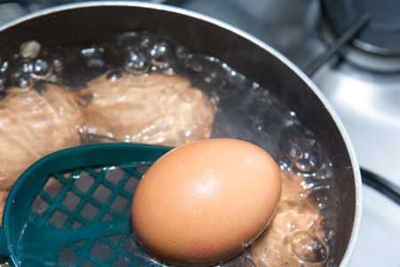 Cooking boiled eggs in a pan of boiling waterの写真素材