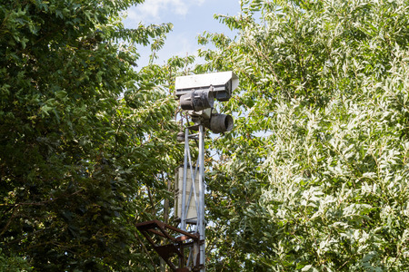 CCTV camera hidden behind trees recording videoの写真素材