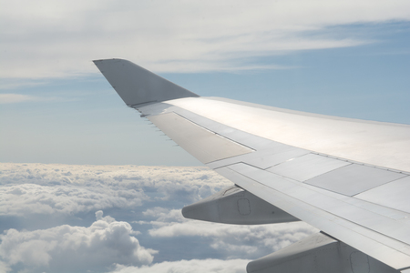 Airplane wing fliying above the clouds in clear skyの写真素材
